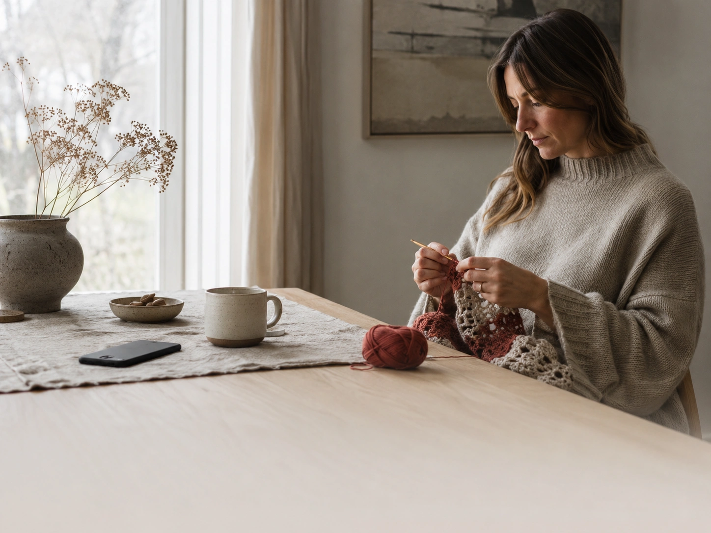 A quiet person sitting with yarn and a phone nearby, choosing to create by hand